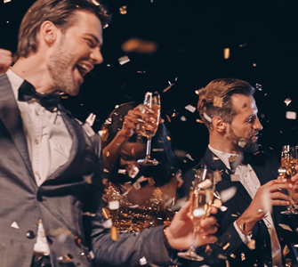 Festlich gekleidete Menschen feiern ausgelassen mit Sektgläsern und Konfetti auf einer Silvesterparty.