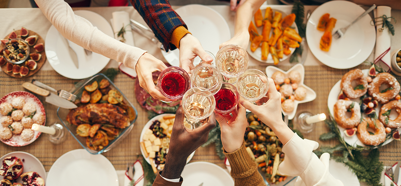 Mehrere Personen stoßen bei einem festlich gedeckten Weihnachtsbrunch mit Wein an.
